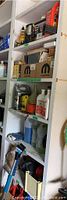 Shelving unit filled with automotive parts, fluids, sprays, and boxed items including MOPAR branded boxes and containers of car care fluids and sprays.