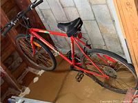 Side view of red Supercycle mountain bike with visible rust and wear.