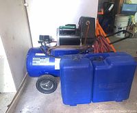 Side view of blue Campbell Hausfeld air compressor with attached red hose and two blue plastic cases in front