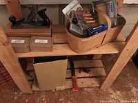 Shelves with tools including screwdrivers, drill bits, screws in basket, and wooden planes