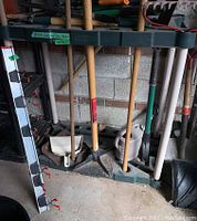 Wide view of Rubbermaid vinyl garden tool caddy rack holding multiple long-handled garden tools.