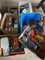 Overview of bins and boxes containing various hardware tools including measuring tapes, nails, fasteners, a blow torch kit, and hand tools.