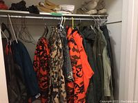 Rack with various hanging hunting jackets and coats in camouflage and orange safety colors