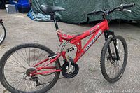 Full side view of red Mongoose Disturb mountain bike showing frame, suspension, wheels, and pedals