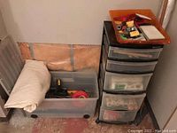 Photo showing rolling clear plastic storage bin with rolled up cloth, tapes, and tools