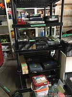 Shelving unit with various tool and hardware cases including plastic containers and tool boxes holding screws, bits, wrenches and multi tool sets.