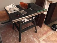 Front and top view of Rockwell 9 inch table saw with accessories including manual, blade guard, and parts on top.