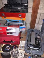 Overview of tools stacked: cutting wheels, sanding discs, router bit packs, Dremel kit case, angle grinder box