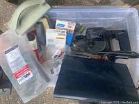 Image showing the Black & Decker belt sander along with sanding sponges and various packs of sandpaper in a plastic bin.