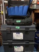 Three tool storage items: two large plastic tool boxes stacked and a hanging black and blue tool bag with multiple pockets