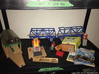 Overview of lot items including wooden station, blue bridge pieces, track segments, whistle, books, lunchbox, and toy figures