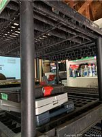 Close-up of the shelving unit legs and grid-pattern shelf surface showing structural details and workshop wear.