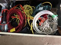 Drawer contents showing work lamp, extension cords, yellow braided rope, and assorted ropes and cords packed inside.
