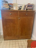 Front view of antique pine cupboard showing two drawers with round metallic knobs, two doors, and surface wear.