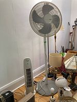 Photo showing Holmes MasterTouch 62 inch oscillating floor fan and smaller CoolWorks tower fan alongside household items.