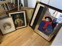 Five framed prints arranged on floor, showing condition, frames, and visible prints including religious and art themes.