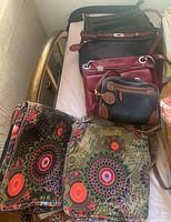 Photo showing six purses, three leather including a Danier leather crossbody, and three fabric with colorful mandala patterns