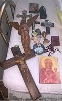 Full view of all religious items arranged on fabric, showing crosses, angel carving, rosary, religious card, and booklet.