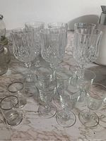 Set of 14 drinking glasses on marble surface, including 6 wine goblets, 6 liqueur glasses, and 2 additional small glasses.