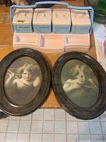 Photo showing pink Clarolyte infant change table caddy with four labeled containers: lotion, pins, swabs, cotton, plus two oval framed prints of a child with a flute.