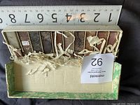 Top-down photo showing 10 soapstone blocks in a green-edged cardboard box with shredded padding, ruler placed across one edge showing measurements in inches.