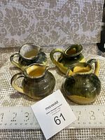 Four yellow and green glazed Inke Pottery jugs displayed on a woven mat with a ruler for size reference and a MaxSold tag showing lot number 61.
