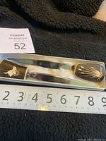Two vintage letter openers resting on black fabric with measuring tape showing length slightly over 8 inches.