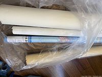Multiple rolled maps wrapped in plastic showing variation in paper quality and size.