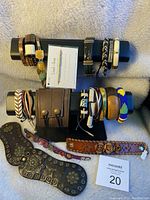 Overview of multiple costume jewelry bracelets arranged on a display stand and around it. Includes leather cuffs, beaded bracelets, fabric wrap bracelets, and metal accented bracelets of various colors and styles.