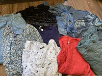 Top-down view showing all items in the lot spread out on wooden floor including light blue jogger jeans and various floral and solid tops.