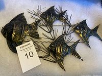 Metal fish wall hanging displayed on white background showing four fish connected by coral-like metal branches, dark metal with bronze highlights.
