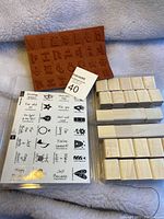 Photo of large orange wooden block stamp, clear stamp sheet, and multiple small wooden stamps together