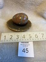 Stone egg placed on geode slice with a measuring tape showing around 4 inches width