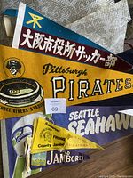 Photo showing six vintage felt pennants featuring Seattle Seahawks, Pittsburgh Pirates, Osaka soccer team, and jamboree flags.