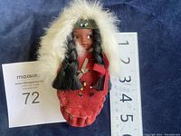 Front view of vintage Native American baby doll in leather moccasin with ruler for size reference