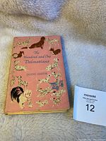 Front cover of the vintage hardcover book The Hundred and One Dalmatians by Dodie Smith with illustrated dust jacket mostly in pink featuring numerous dogs including Dalmatians.