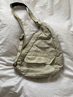 Front view of cream/off-white Ameribag purse showing flap pocket and adjustable shoulder strap with visible ink stain.