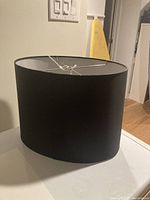 Front side view of the black oval fabric lampshade showing full shape and smooth fabric texture.