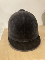 Front angled view of black velvet riding helmet showing surface wear.