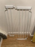 Photo of the compact frame of the white metal baby gate without extensions showing vertical bars and mounting pads.