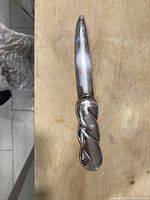 Top view of letter opener showing full length and twisted handle design on a wooden surface.