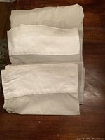Folded dove grey cotton/linen blend sheets arranged on wooden floor showing fabric texture and color.