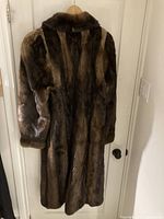 Rear view of full-length brown sheared otter fur coat on hanger