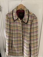 Full front view of women's wool Coach car coat jacket with multicoloured houndstooth pattern and leather trim details, button fastening visible.