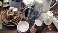 Wide view of baskets, salt and pepper shakers, jug, glasses, and canisters grouped on a wooden table
