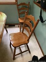 Two wooden dining chairs with ladder backs and contoured seats positioned near a table.