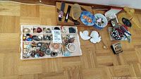 Overview of tray with costume jewelry, hairbrush, fan, floral tin, wooden box and plaster angels