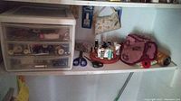 Wide shot of shelf with organizer and sewing supplies arranged including scissors, pincushions, thread spools, and fabric