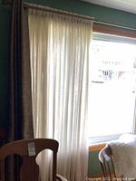 Curtain panels hung on rod showing sheer fabric with flecks, with natural light coming through window behind.