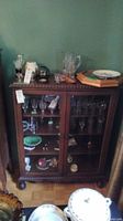 Front view of solid wood display cabinet with glass-front doors showcasing interior shelving.